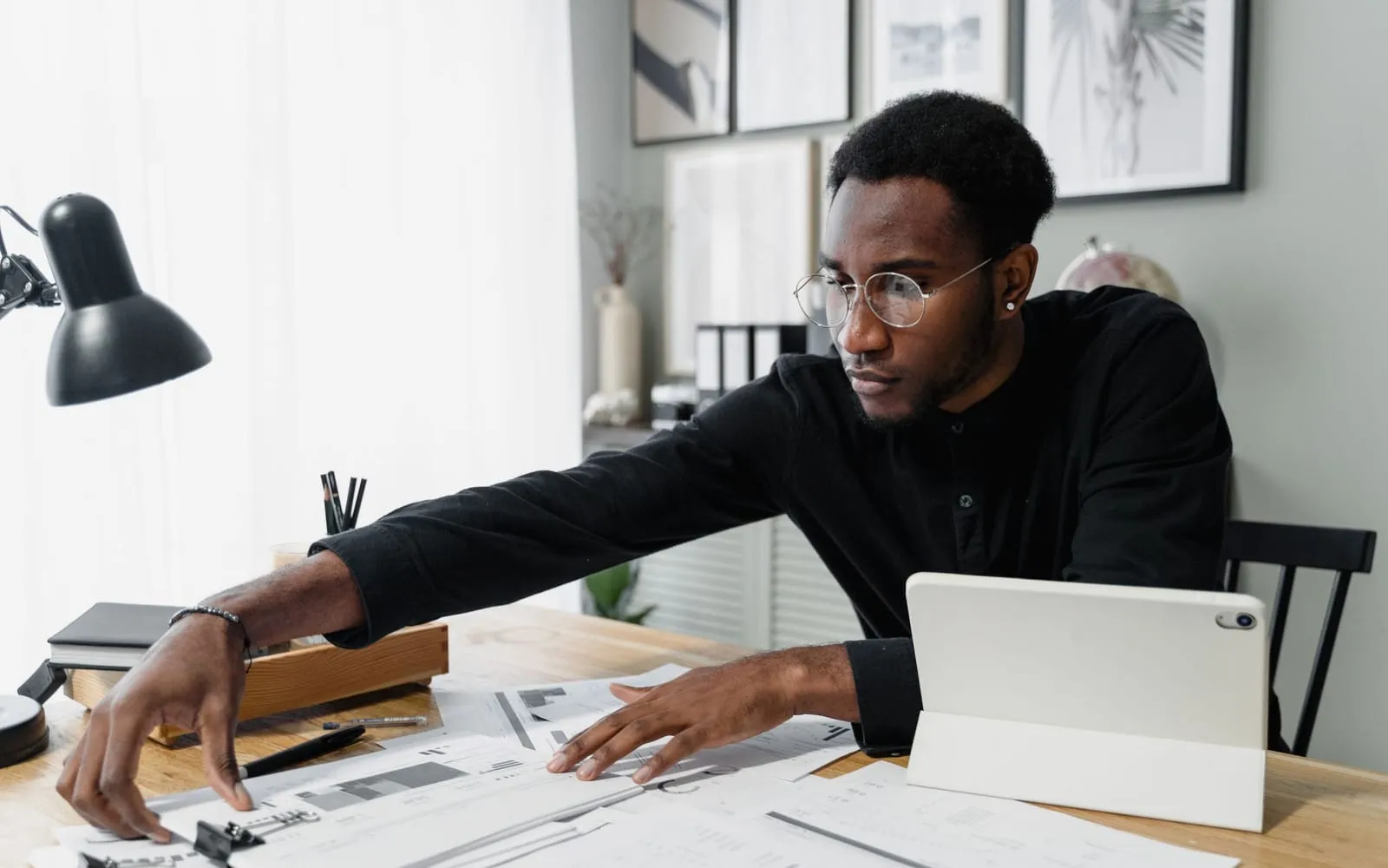 An accountant reviewing printed reports beside a tablet at a bright desk